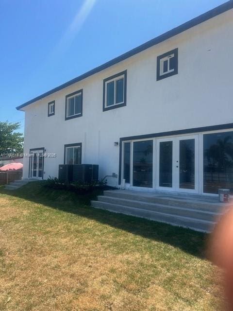 rear view of house featuring a yard, french doors, and stucco siding