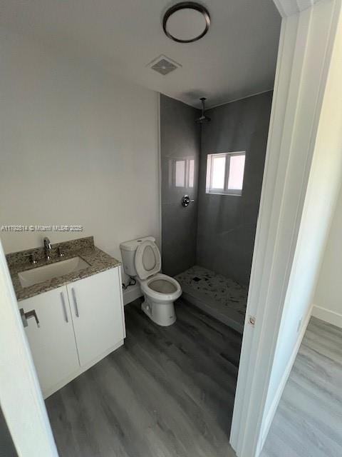 bathroom with toilet, visible vents, a shower stall, and wood finished floors