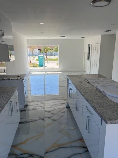 kitchen featuring white cabinetry, light stone counters, modern cabinets, and marble finish floor