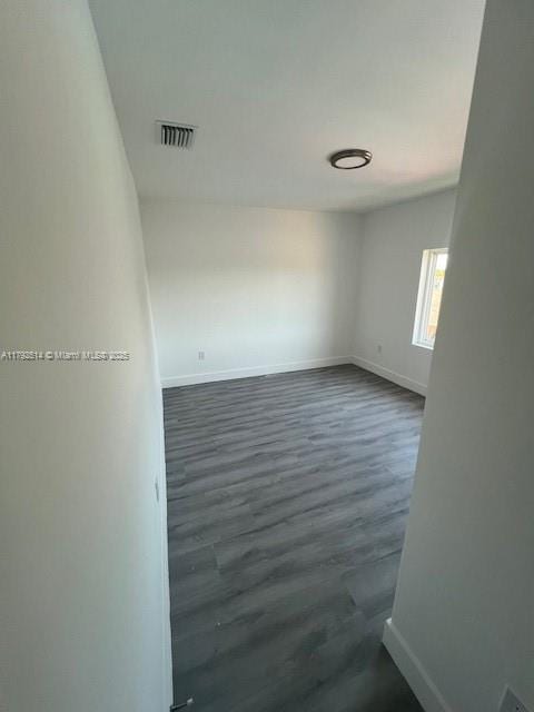 spare room with dark wood-style flooring, baseboards, and visible vents