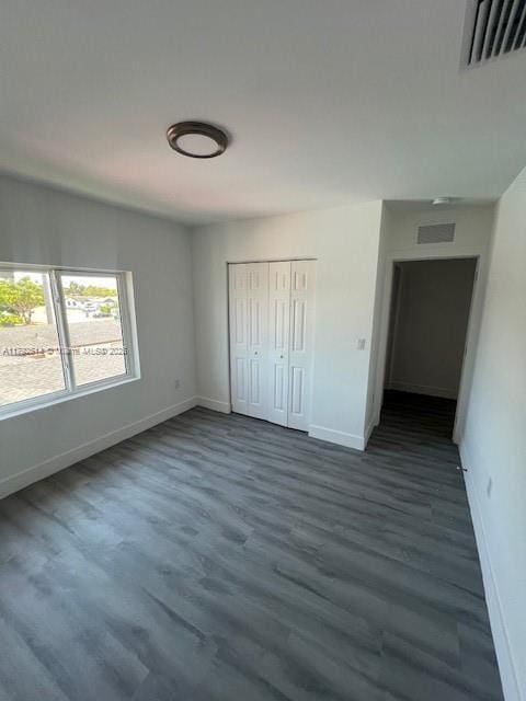 unfurnished bedroom featuring baseboards, visible vents, and wood finished floors