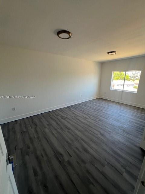 empty room featuring dark wood-style flooring and baseboards