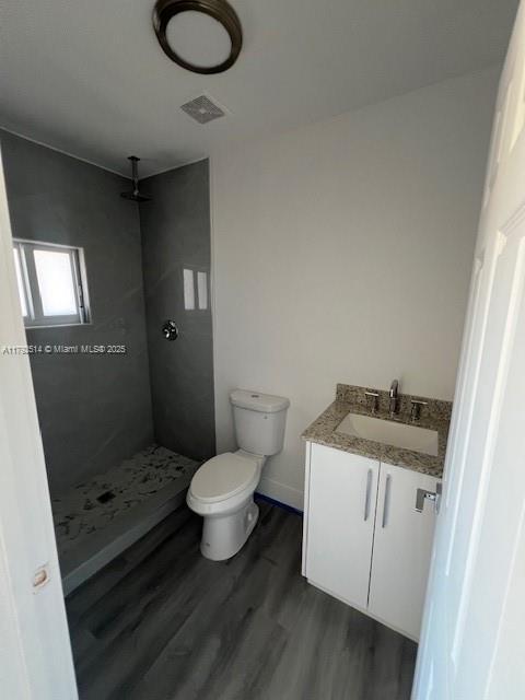 bathroom featuring visible vents, a shower stall, wood finished floors, vanity, and toilet