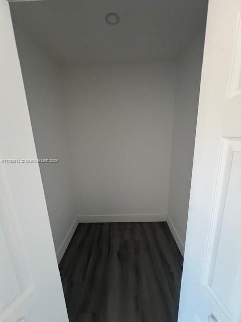 unfurnished room featuring baseboards and dark wood-style flooring