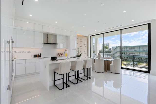 4008 NE 167th St Unit 6, North Miami Beach, FL 33160 - kitchen featuring modern cabinets, a breakfast bar area, wall chimney range hood, white cabinetry, and light tile patterned floors