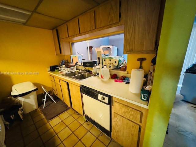 kitchen with white dishwasher, a sink, light countertops, brown cabinetry, and light tile patterned floors