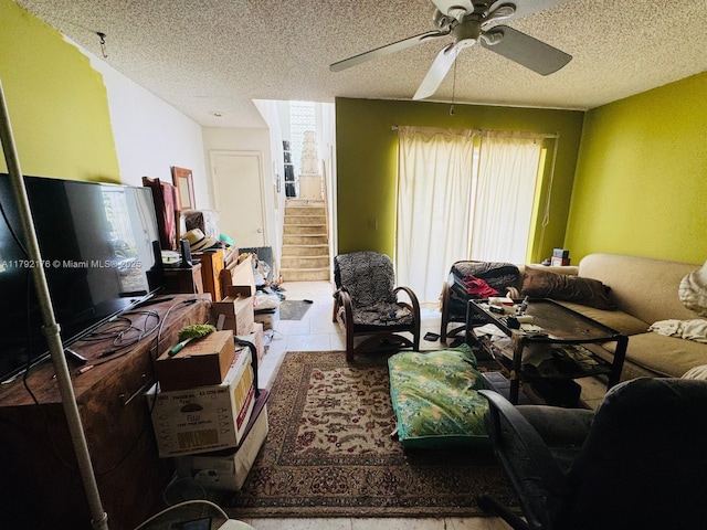 living room with a ceiling fan, a textured ceiling, and stairs
