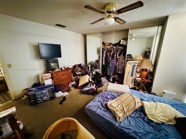 carpeted bedroom with a closet, a ceiling fan, a textured ceiling, and visible vents