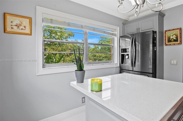 kitchen with gray cabinets, light stone countertops, stainless steel fridge with ice dispenser, an inviting chandelier, and ornamental molding