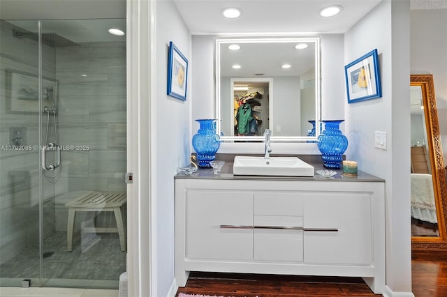 bathroom with vanity, a shower stall, recessed lighting, and wood finished floors