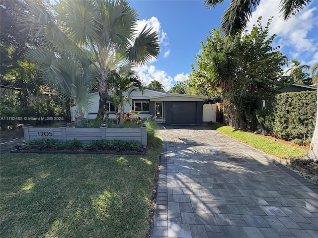 1205 NE 17th Ter, Fort Lauderdale, FL 33304 - ranch-style house featuring decorative driveway, an attached garage, fence, and a front lawn