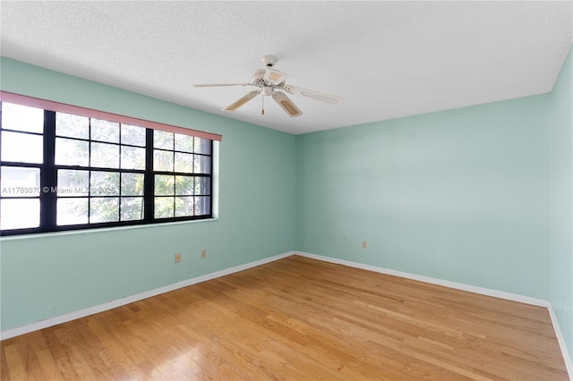 unfurnished room featuring baseboards, a ceiling fan, light wood finished floors, and a textured ceiling