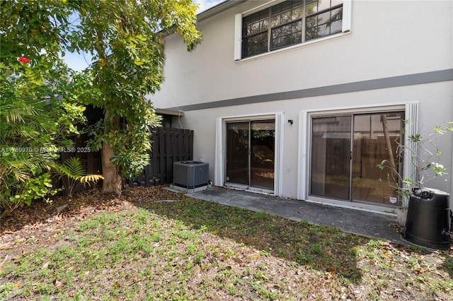 back of house featuring fence, central AC unit, and stucco siding