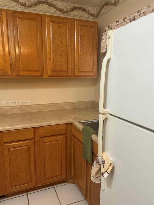 2900 N Pine Island Rd Unit 307, Sunrise, FL 33322 - kitchen with freestanding refrigerator, light tile patterned floors, brown cabinets, and light countertops