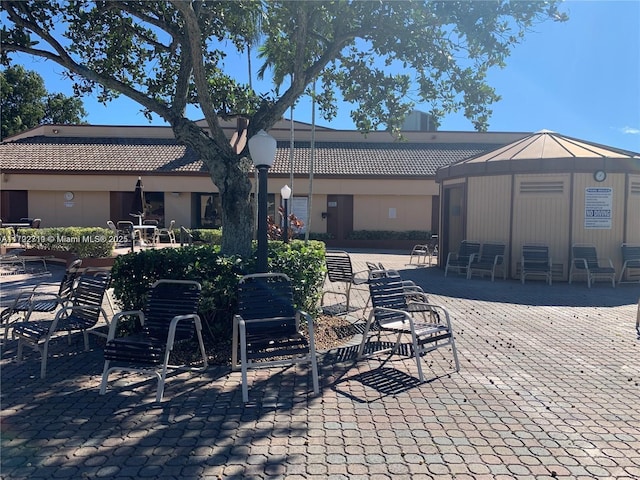 2900 N Pine Island Rd Unit 307, Sunrise, FL 33322 - rear view of property featuring a tiled roof, a chimney, and a patio area