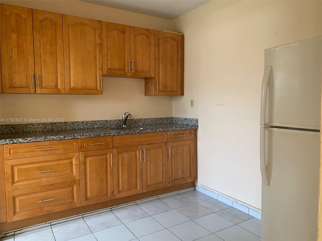 2381 SW 7th St, Miami, FL 33135 - kitchen with freestanding refrigerator, brown cabinets, dark stone counters, and light tile patterned flooring