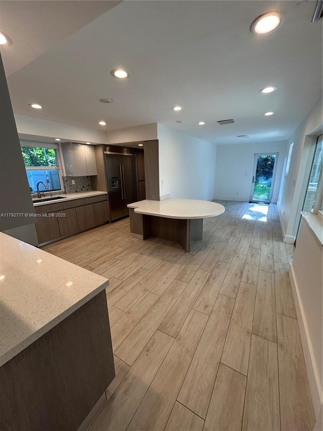 interior space with baseboards, modern cabinets, light countertops, paneled built in refrigerator, and light wood-style flooring