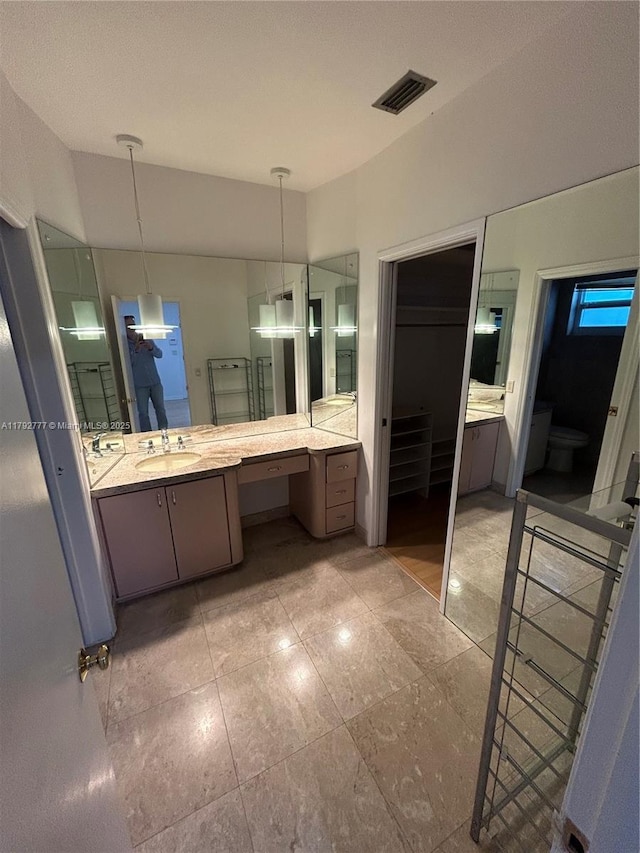 bathroom featuring vanity, toilet, and visible vents