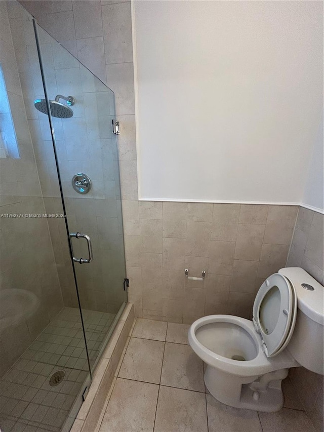 full bath with toilet, tile walls, a shower stall, and tile patterned flooring
