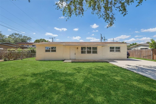 rear view of house with fence and a yard