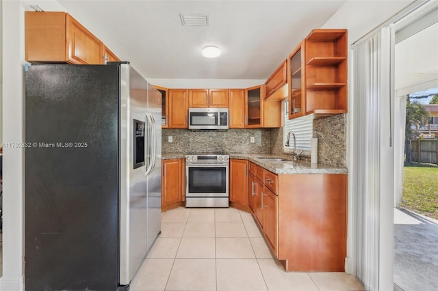 kitchen featuring visible vents, brown cabinets, a sink, light stone counters, and stainless steel appliances