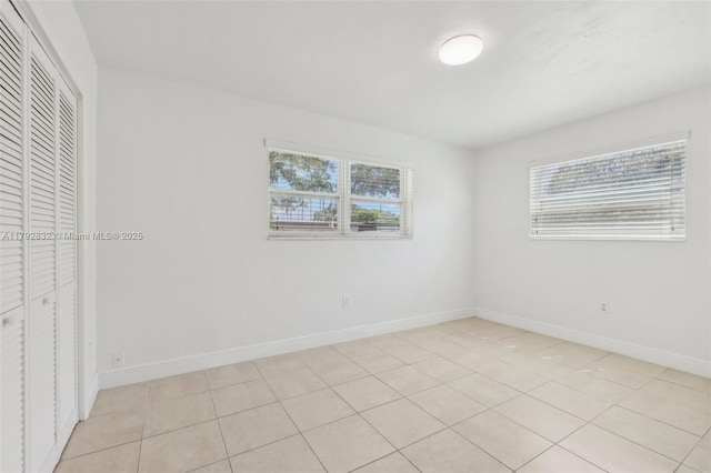 unfurnished bedroom with baseboards, light tile patterned floors, and a closet