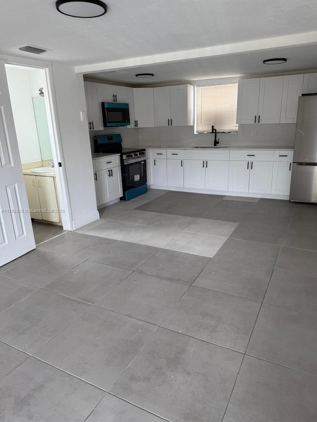 2291 W 53rd Pl Unit 2291, Hialeah, FL 33016 - kitchen with visible vents, light tile patterned flooring, white cabinets, a sink, and appliances with stainless steel finishes