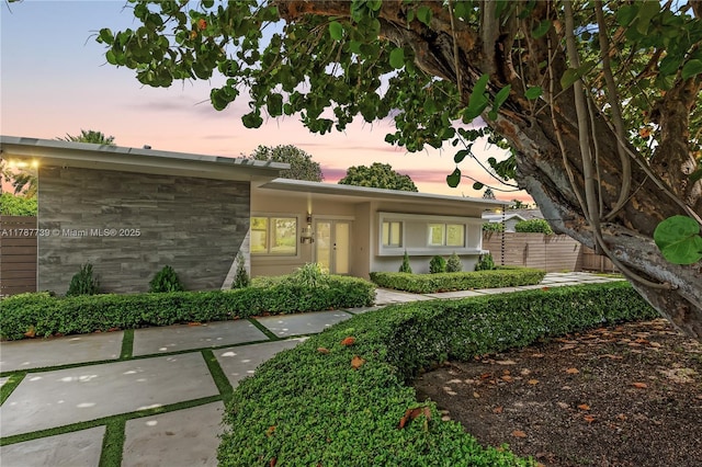 view of front of home with fence and stone siding