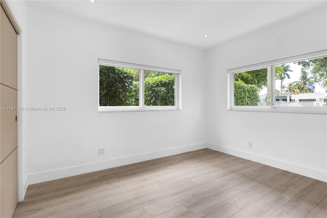unfurnished room featuring baseboards, a wealth of natural light, and light wood-style floors