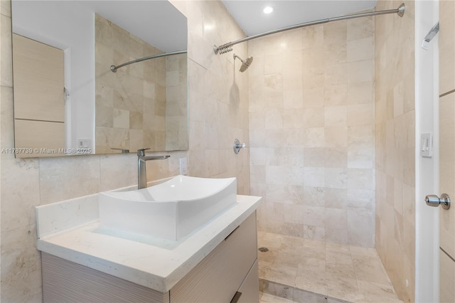 bathroom featuring tile walls, tiled shower, and vanity