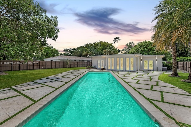 view of pool with french doors, a fenced in pool, a fenced backyard, a lawn, and a patio