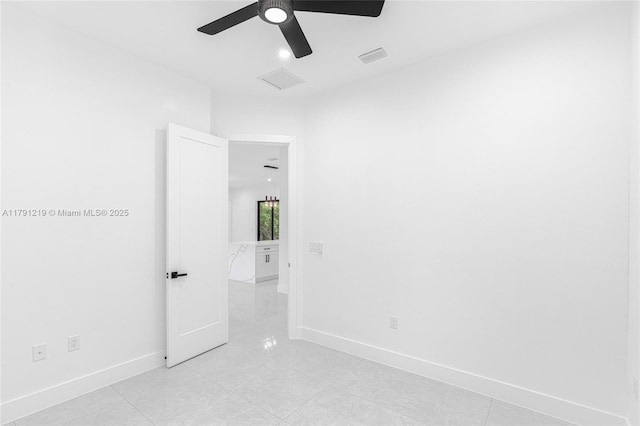 spare room featuring light tile patterned flooring, ceiling fan, visible vents, and baseboards