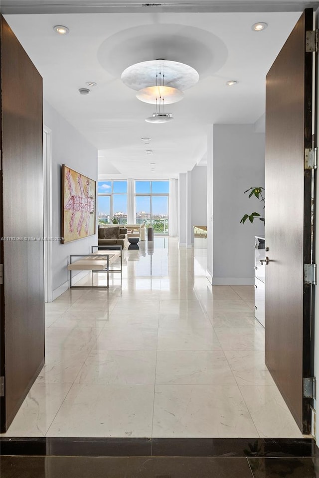 hallway with baseboards, recessed lighting, and floor to ceiling windows