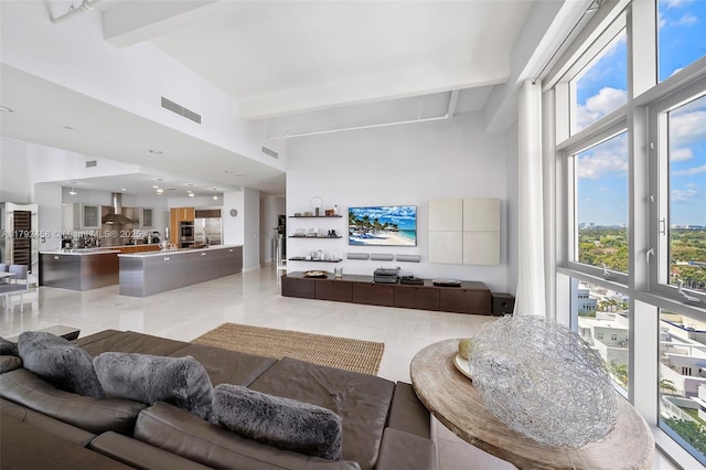 living room with a high ceiling, beam ceiling, and visible vents