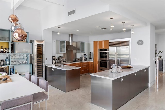 kitchen with appliances with stainless steel finishes, a sink, wall chimney exhaust hood, a peninsula, and visible vents