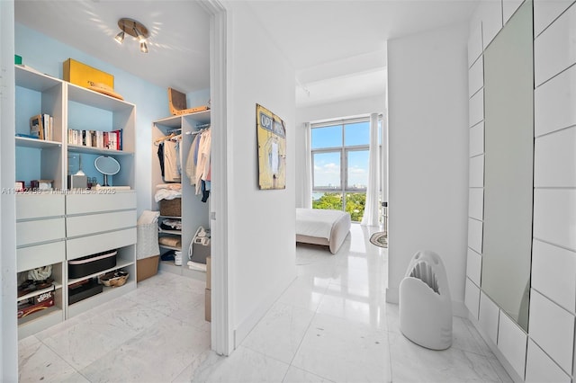 walk in closet featuring marble finish floor