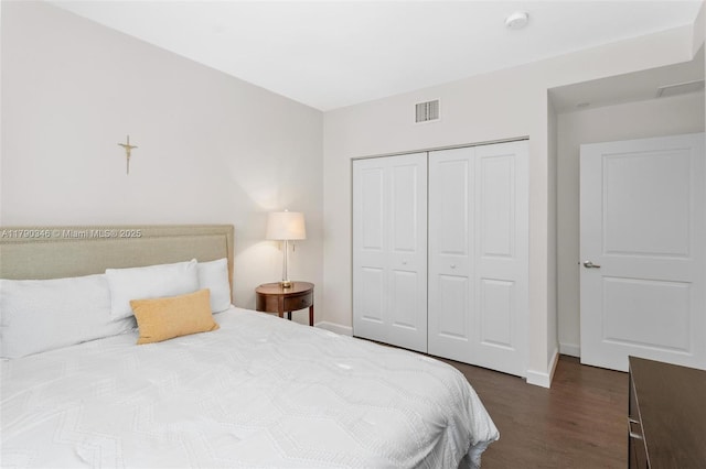 bedroom featuring dark wood-style flooring, baseboards, visible vents, and a closet