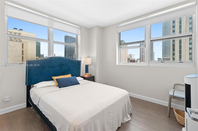 bedroom with baseboards, wood finished floors, and multiple windows