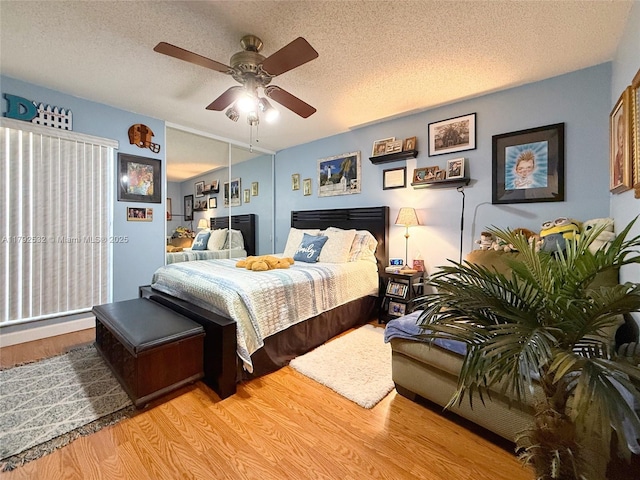 bedroom featuring a ceiling fan, light wood finished floors, and a textured ceiling