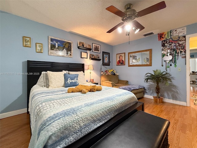 bedroom featuring a ceiling fan, baseboards, visible vents, and wood finished floors