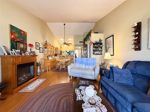 living area with a ceiling fan, wood finished floors, and vaulted ceiling