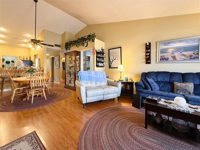living room featuring ceiling fan, wood finished floors, and vaulted ceiling