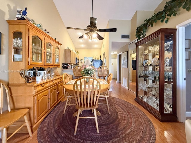 dining area featuring high vaulted ceiling, a ceiling fan, light wood finished floors, and visible vents