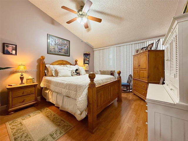 bedroom featuring wood finished floors, ceiling fan, a textured ceiling, and lofted ceiling