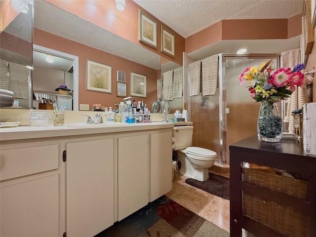 full bathroom with vanity, a textured ceiling, toilet, and a shower stall