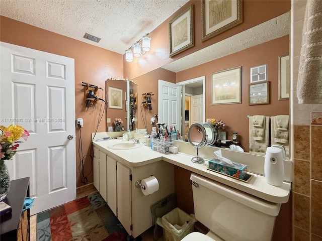 bathroom featuring toilet, a textured ceiling, visible vents, and vanity