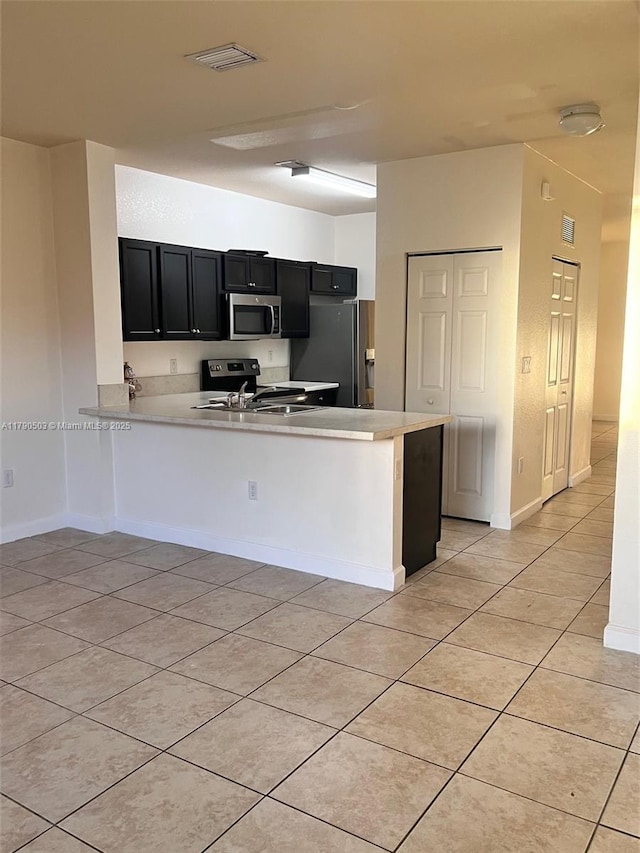 112 SE 28th Ter Unit 4, Homestead, FL 33033 - kitchen featuring visible vents, a peninsula, dark cabinetry, light tile patterned floors, and stainless steel appliances