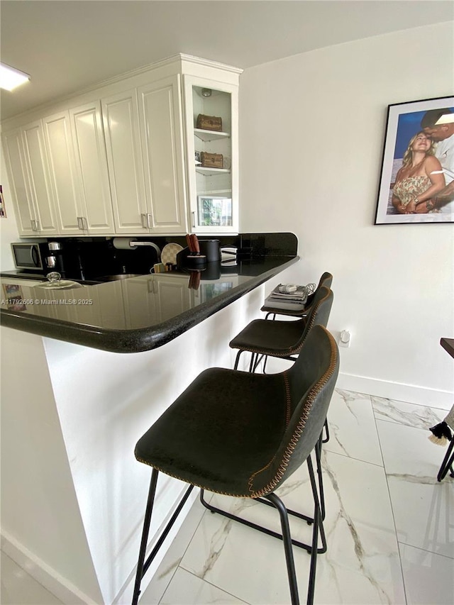 1700 NW N River Dr Unit 501, Miami, FL 33125 - kitchen featuring dark countertops, baseboards, white cabinets, and marble finish floor