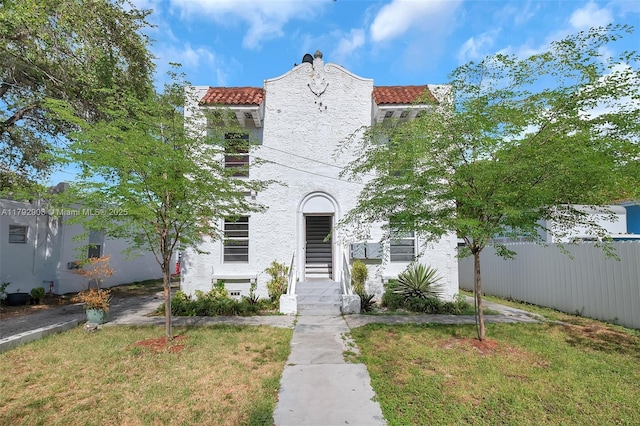 mediterranean / spanish-style home with a tiled roof, a front lawn, and stucco siding