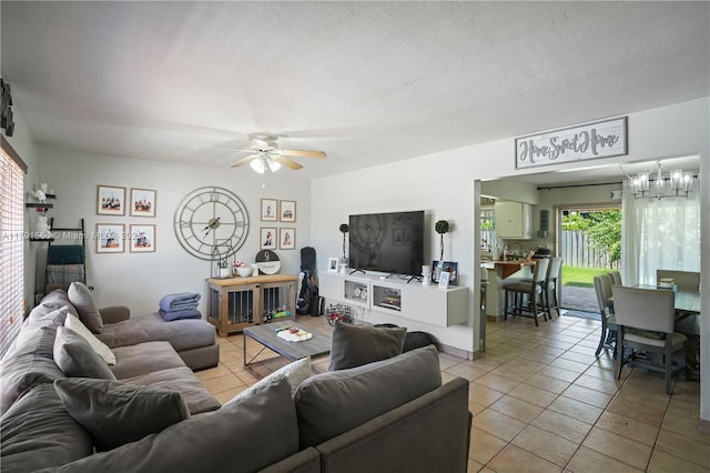 living area with ceiling fan with notable chandelier and light tile patterned flooring